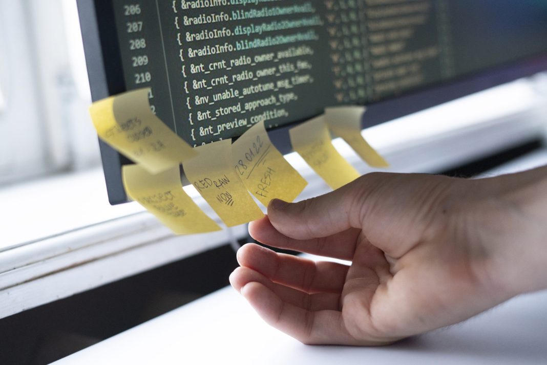 a employee in office attach the paper note sticker to the computer monitor screen