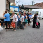 Camion încărcat cu marfă de producători români la piața din Cisnădie, clienți în jur